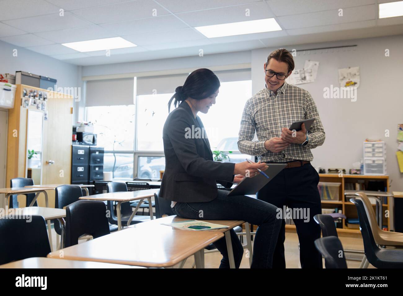 High school teachers with digital tablets talking in classroom Stock