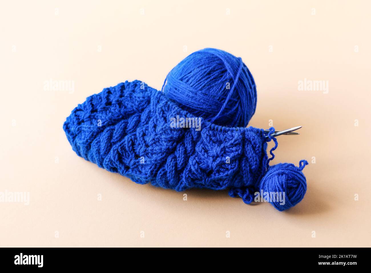 Knitting blue warm clothes with knitting needles and blue balls of thread on an orange background Stock Photo