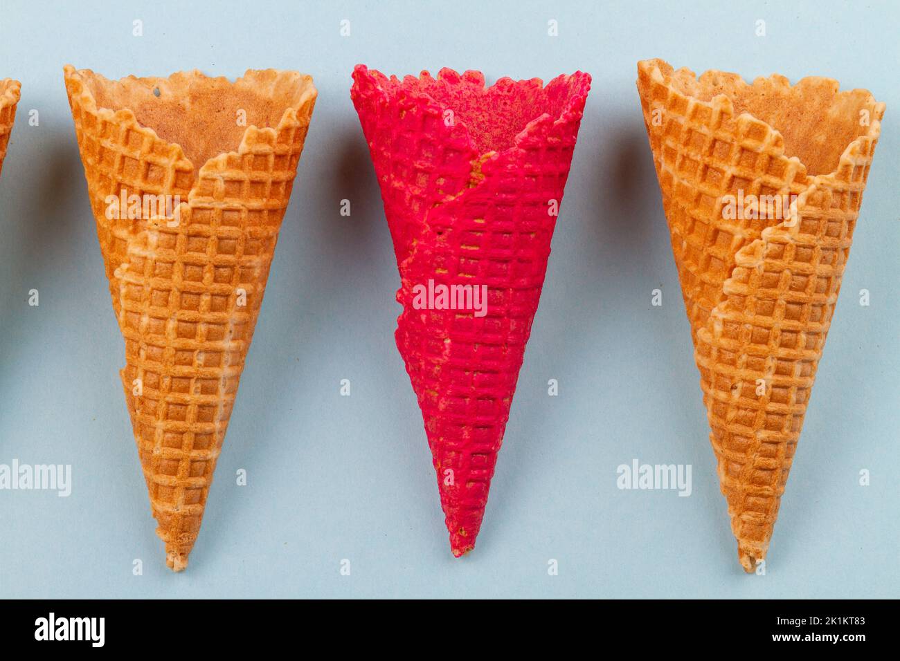 Close up red waffle ice cream cones and ordinary ones. Blue pastel background. Stock Photo
