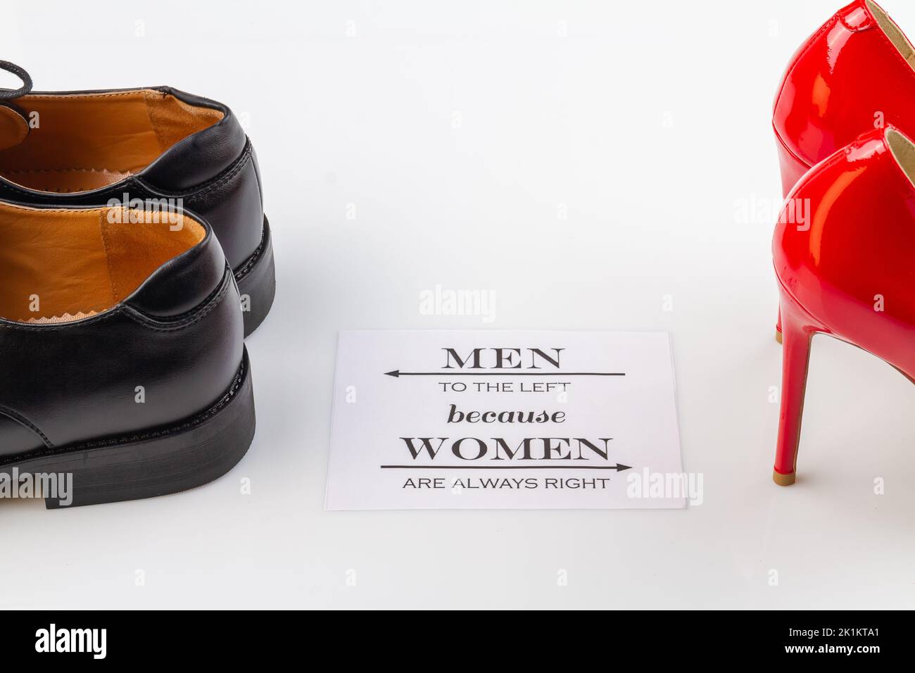 Men to the left because women are always right. Mens and womens shoes on white surface. Stock Photo