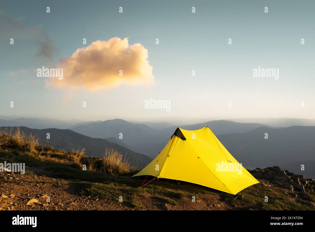 Yellow tent against the backdrop of an incredible mountain landscape during morning sunrise. Amazing highland. Tourism concept Stock Photo