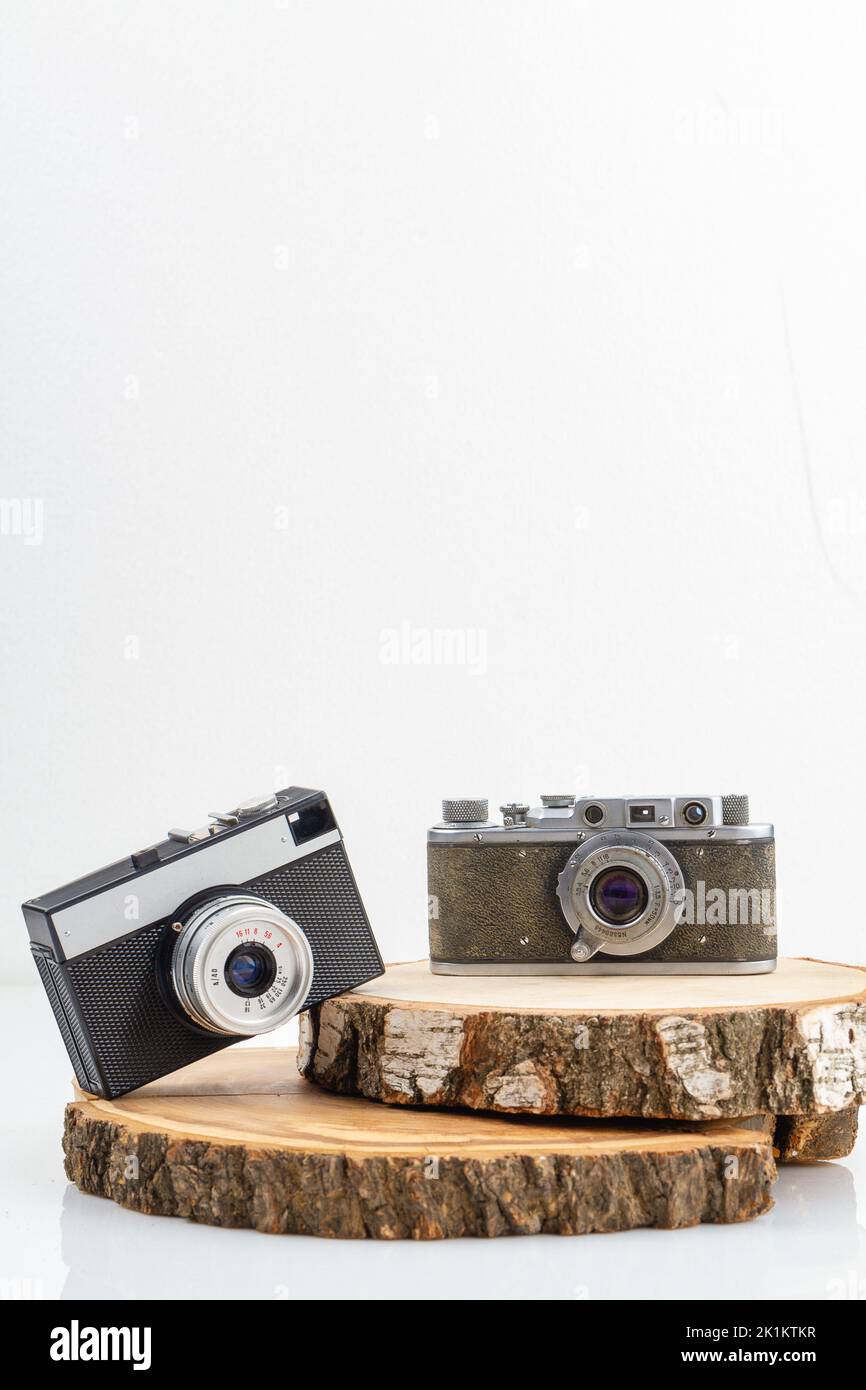 Two retro photo cameras on wooden boards. Concept of mens and womens cameras. Vertical shot isolated on white. Stock Photo