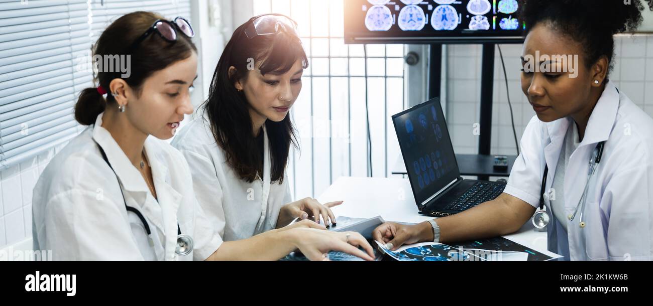 Team of female doctor check on scan results paper and looking at monitors in laboratory and plan and share medical knowledge and experience benefits h Stock Photo