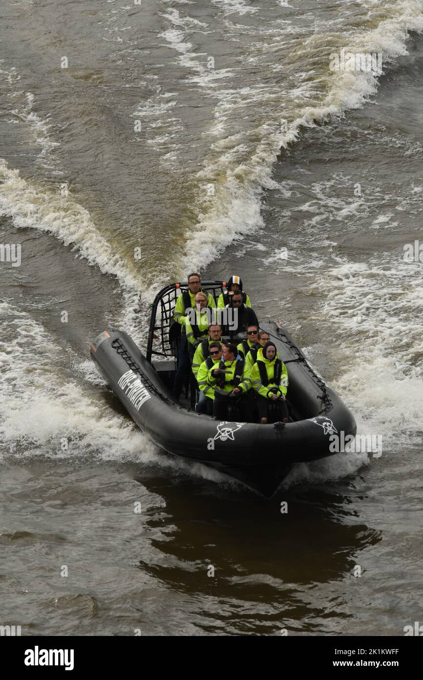 The vertical view of people with green life jackets in the RIB speedboat on the waves Stock Photo