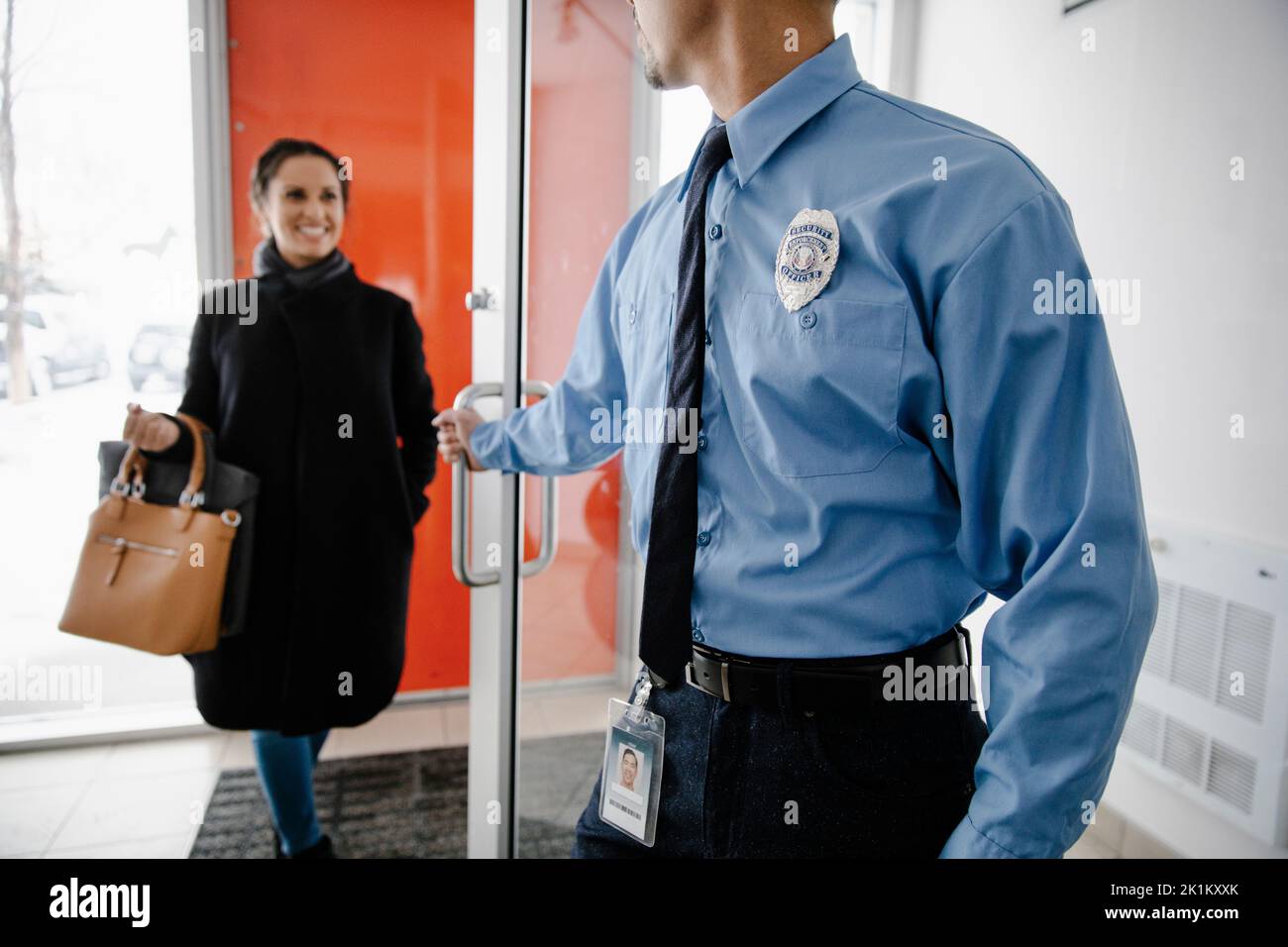 Security guard wearing badge opening door Stock Photo Alamy