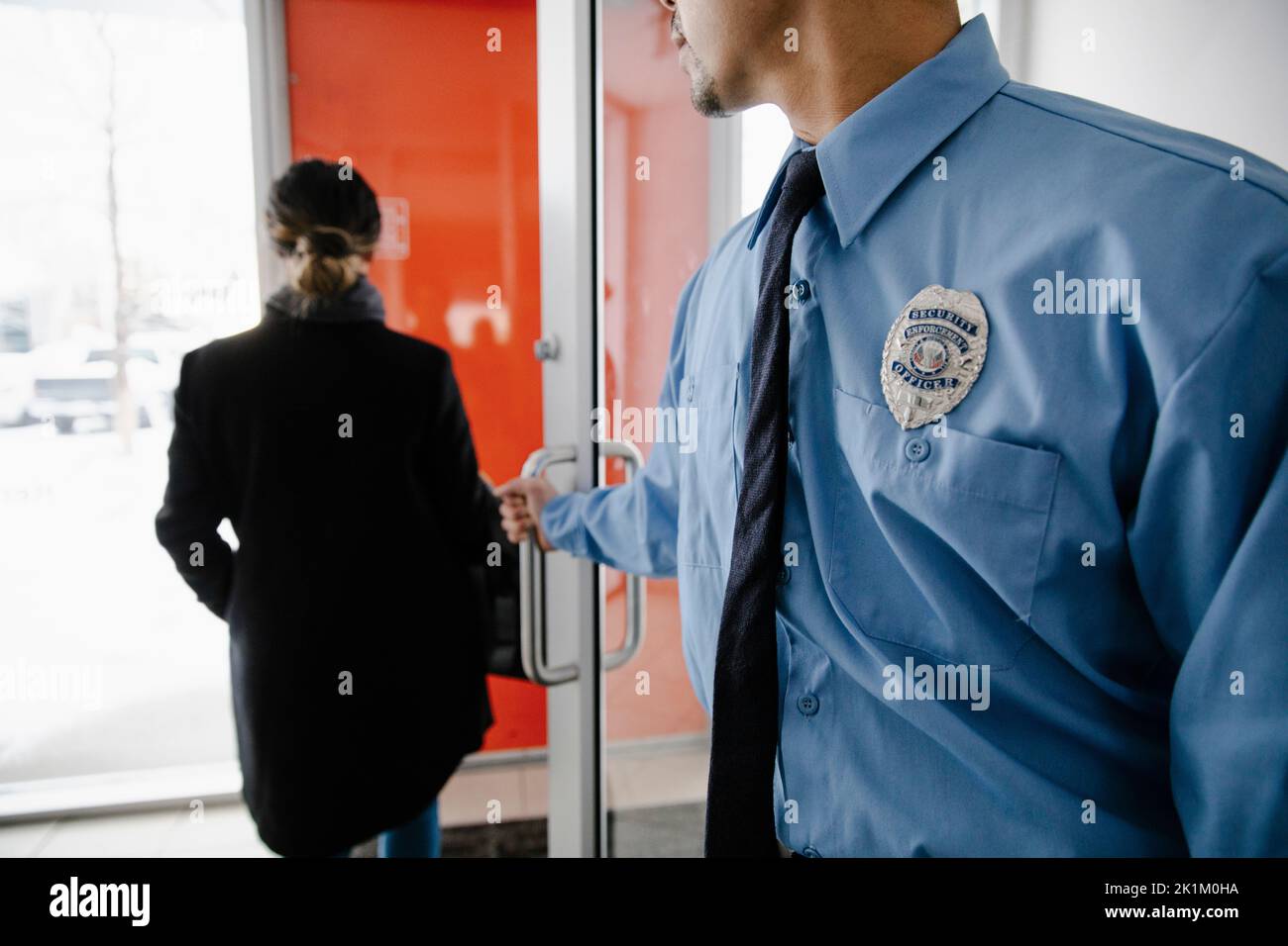 Security guard wearing badge opening door Stock Photo Alamy
