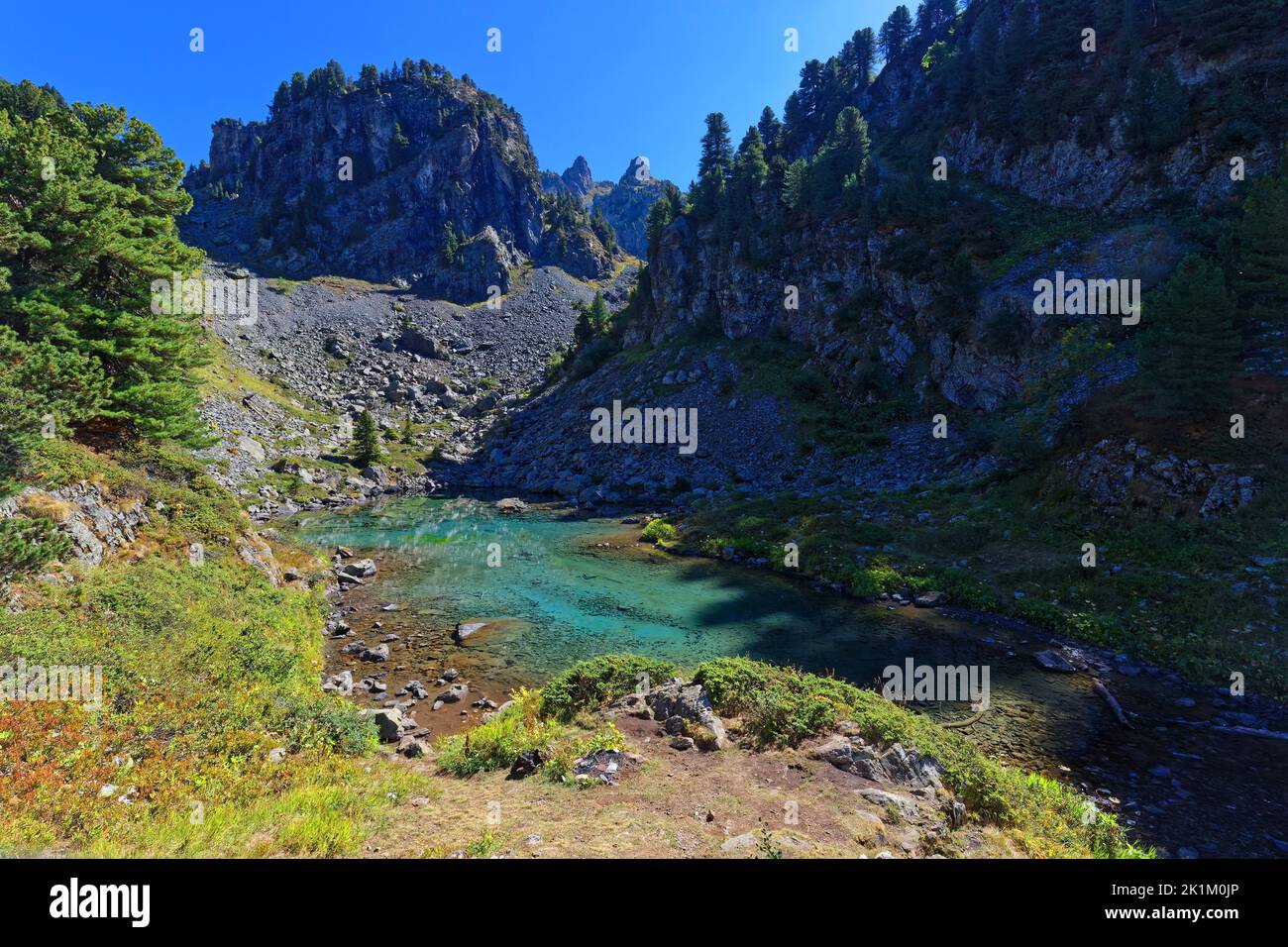 Green colors of Leama lake in its small valley Stock Photo