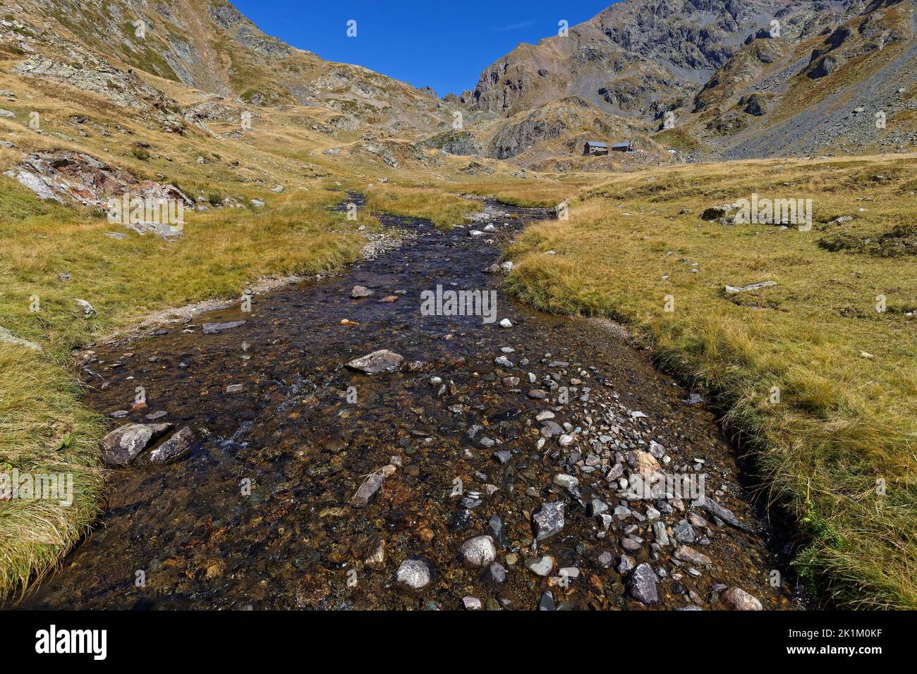 The creek on La Pra plateau and mountain hust in background Stock Photo