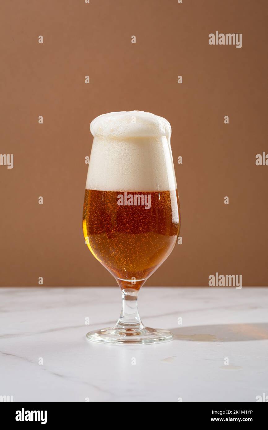 One glass amber golden beer overflowing food and drink Stock Photo