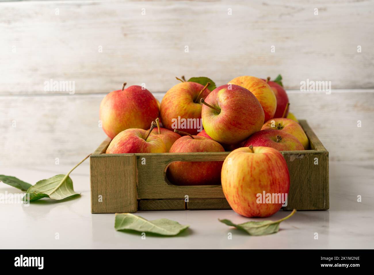 Close up of Yellow and red apples in wooden crate on light surface food harvest concept Stock Photo