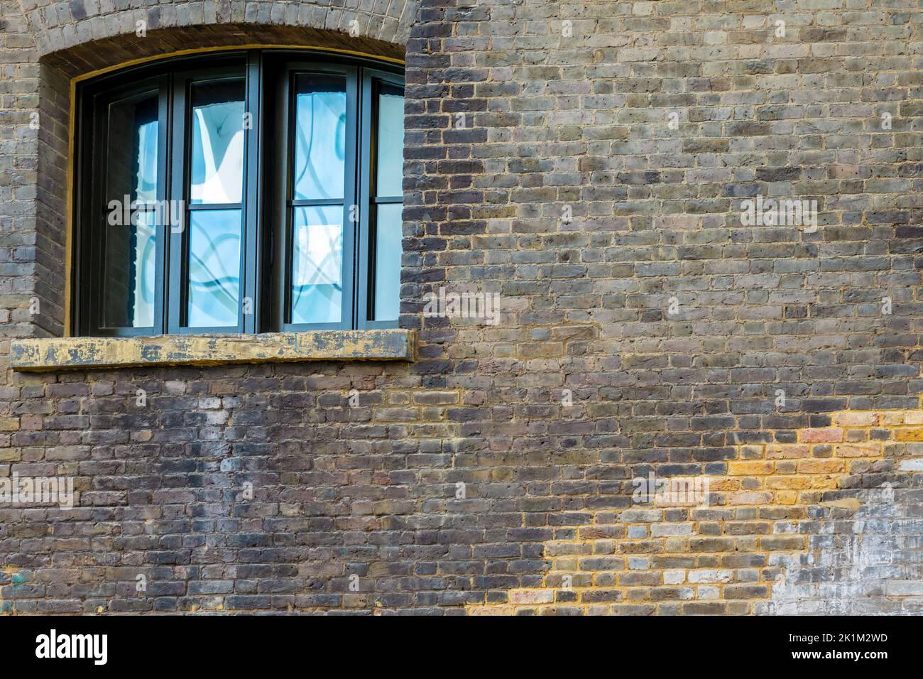 Window with reflection in an old brick wall Stock Photo