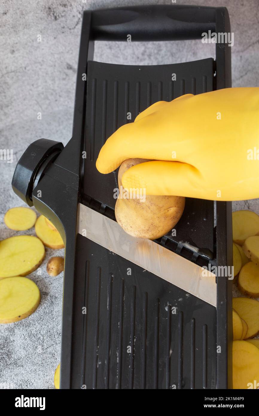 https://c8.alamy.com/comp/2K1M4P9/person-slicing-potato-on-a-kitchen-mandolin-cutter-on-a-concrete-background-2K1M4P9.jpg