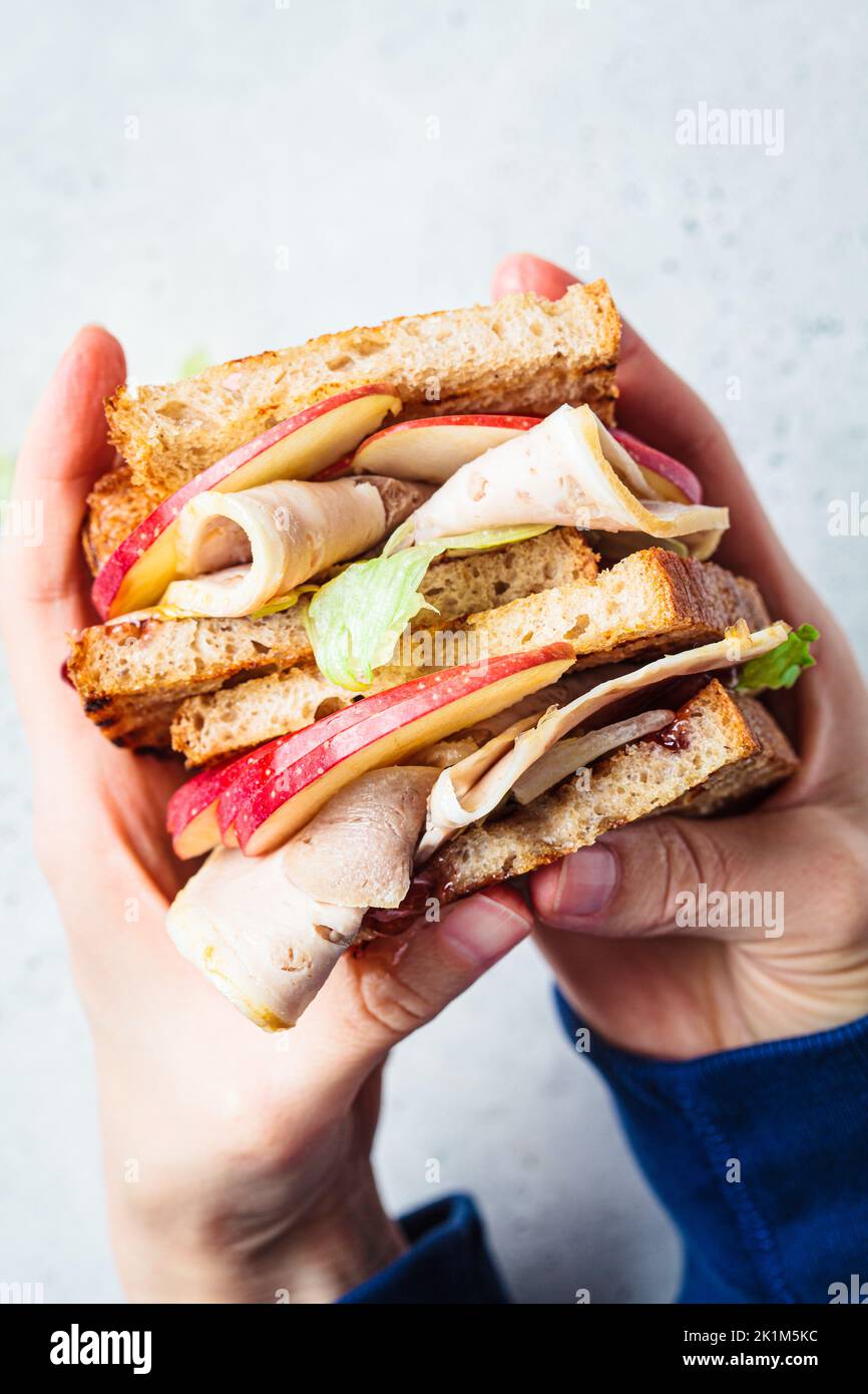Turkey and apple sandwich in hands, top view. Thanksgiving leftovers concept. Stock Photo