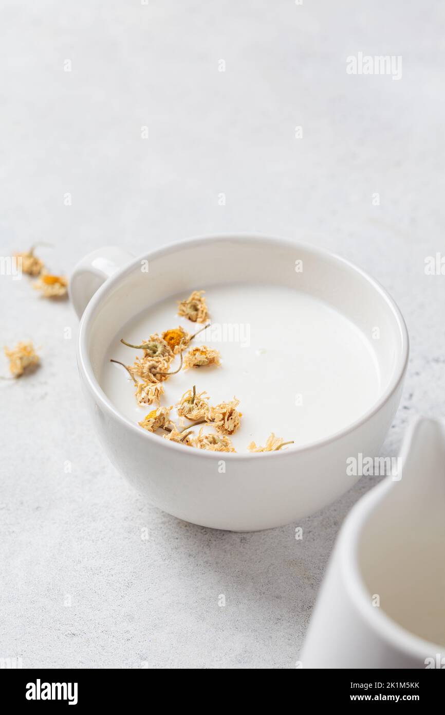 Chamomile moon milk in a white cup. Ayurveda drink, chamomile latte tea. Stock Photo