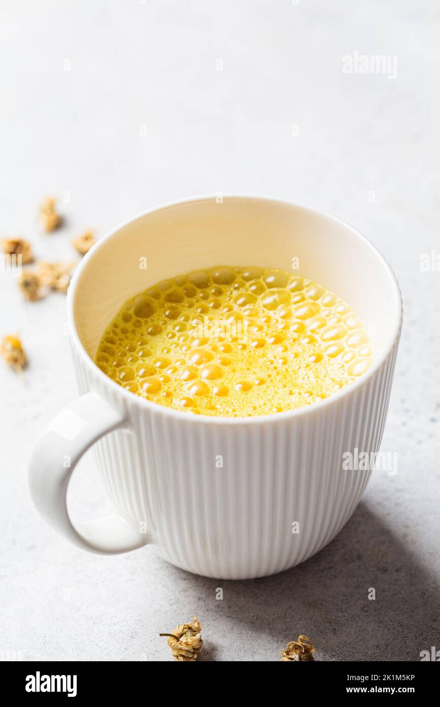 Golden turmeric chamomile moon milk in a white cup. Ayurveda drink, healthy lifestyle, remedy for insomnia. Stock Photo