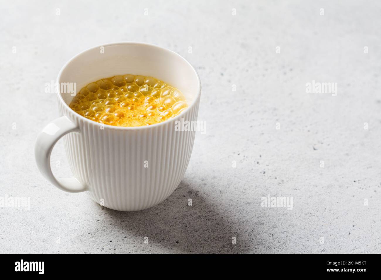 Golden turmeric moon milk in a white cup. Ayurveda drink, healthy lifestyle, remedy for insomnia. Stock Photo