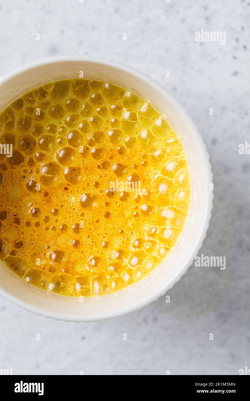 Golden turmeric moon milk in a white cup, top view. Ayurveda drink, healthy lifestyle, remedy for insomnia. Stock Photo
