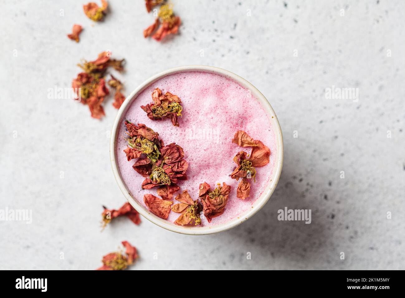 Pink flower moon milk in a white cup, top view. Ayurveda drink, healthy lifestyle, remedy for insomnia. Stock Photo
