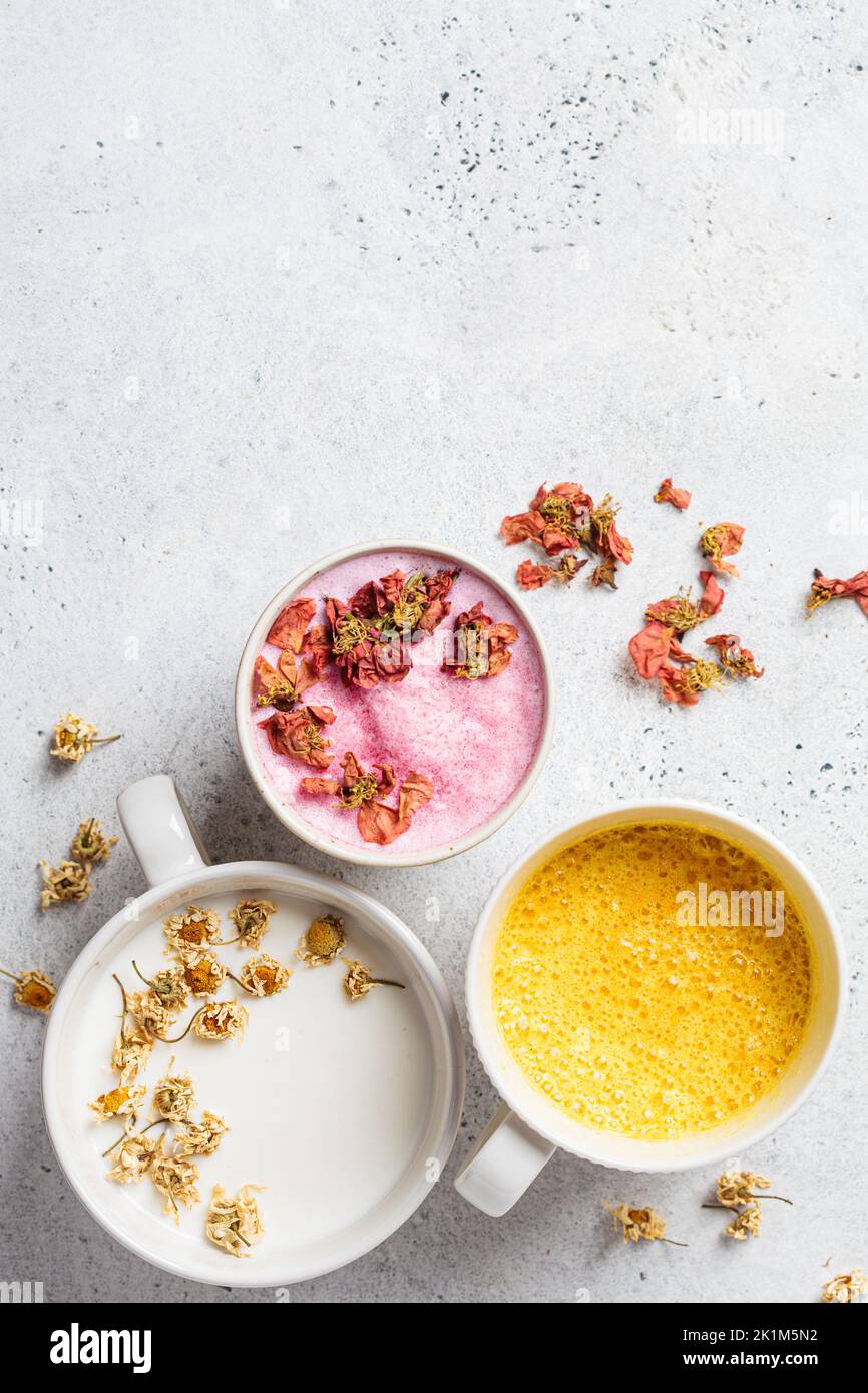 Different types of moon milk: rose flower, golden turmeric and chamomile in white cups, top view. Ayurveda drink, healthy lifestyle, remedy for insomn Stock Photo