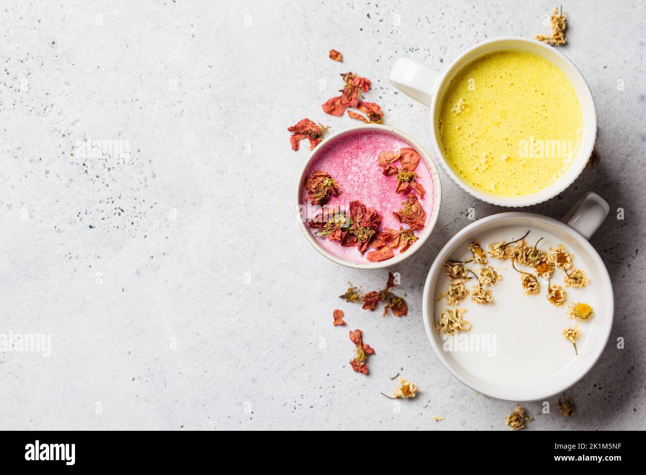 Different types of moon milk: rose flower, golden turmeric and chamomile in white cups, top view. Ayurveda drink, healthy lifestyle, remedy for insomn Stock Photo