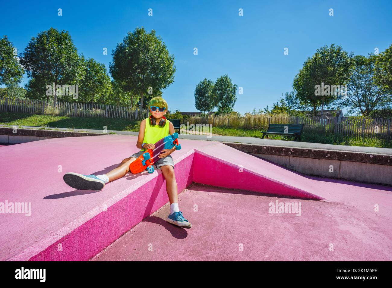 Portrait of a cute young preteen boy with green hair sit on ramp Stock Photo