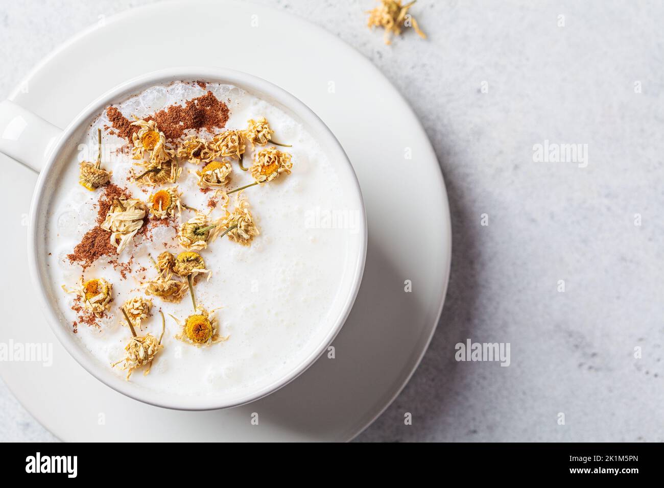 Chamomile moon milk with cinnamon in a white cup, top view. Ayurveda drink, chamomile latte tea. Stock Photo