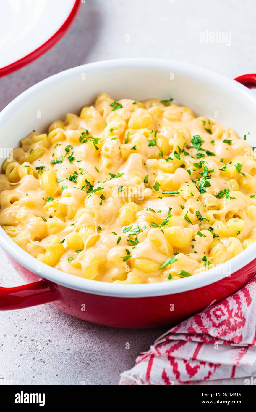 Mac and cheese in red pot, close-up. Traditional American food. Stock Photo