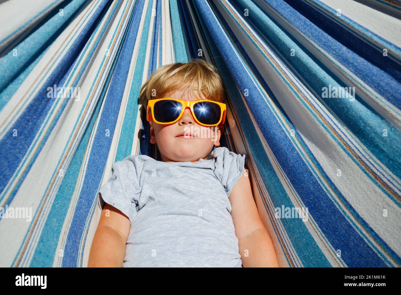 Calm little blond boy with sunglasses rest in hammock Stock Photo