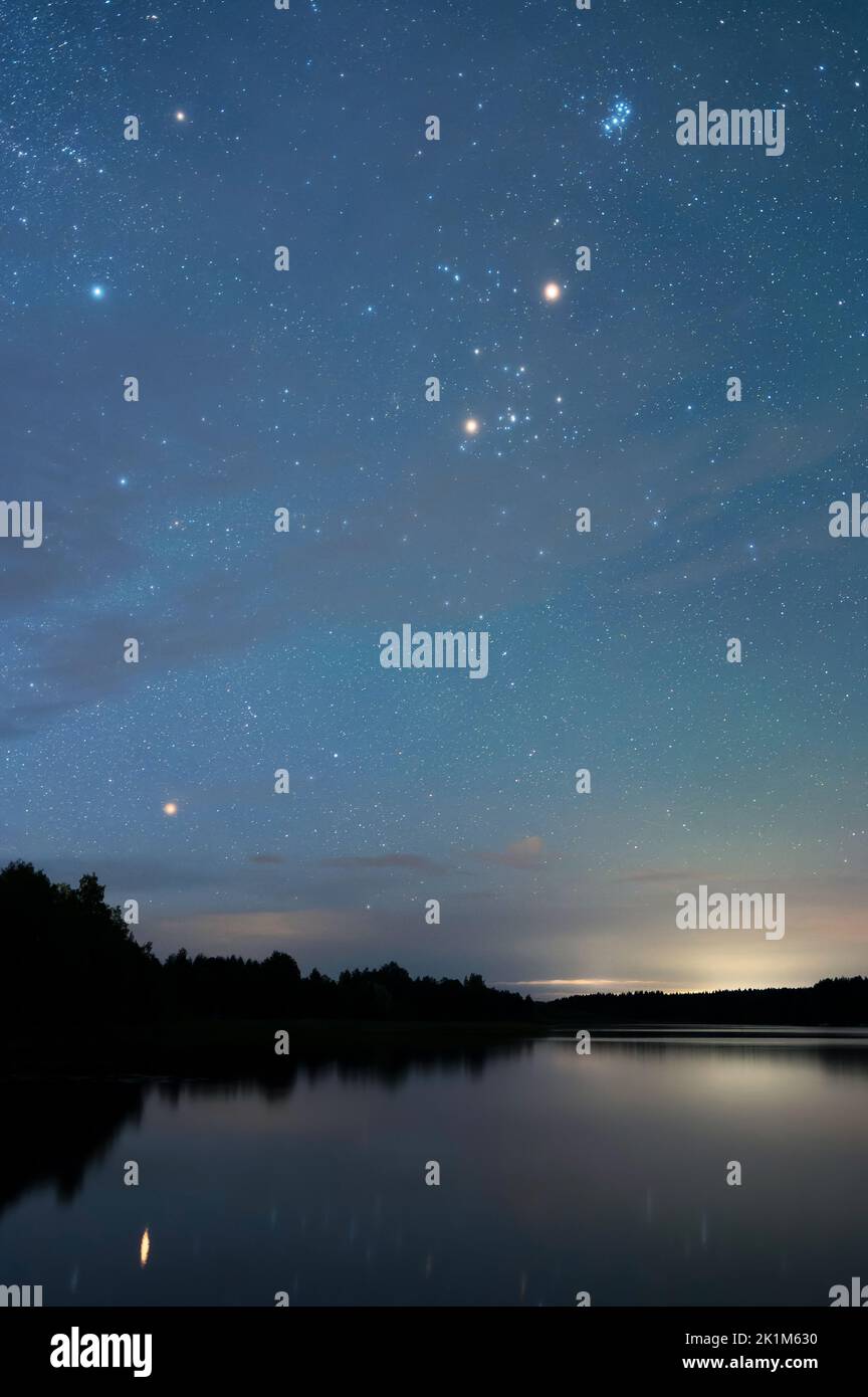 Autumn night landscape under starry sky. Stars reflecting from calm water surface. Stock Photo