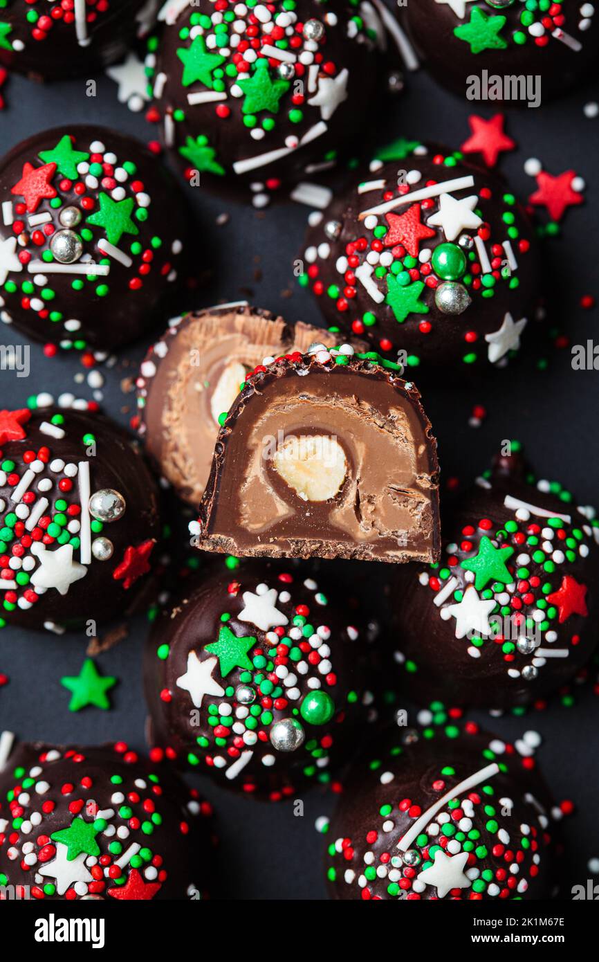 Christmas handmade chocolate balls with holiday sprinkles on black background. DIY holiday cooking, dessert recipe. Stock Photo