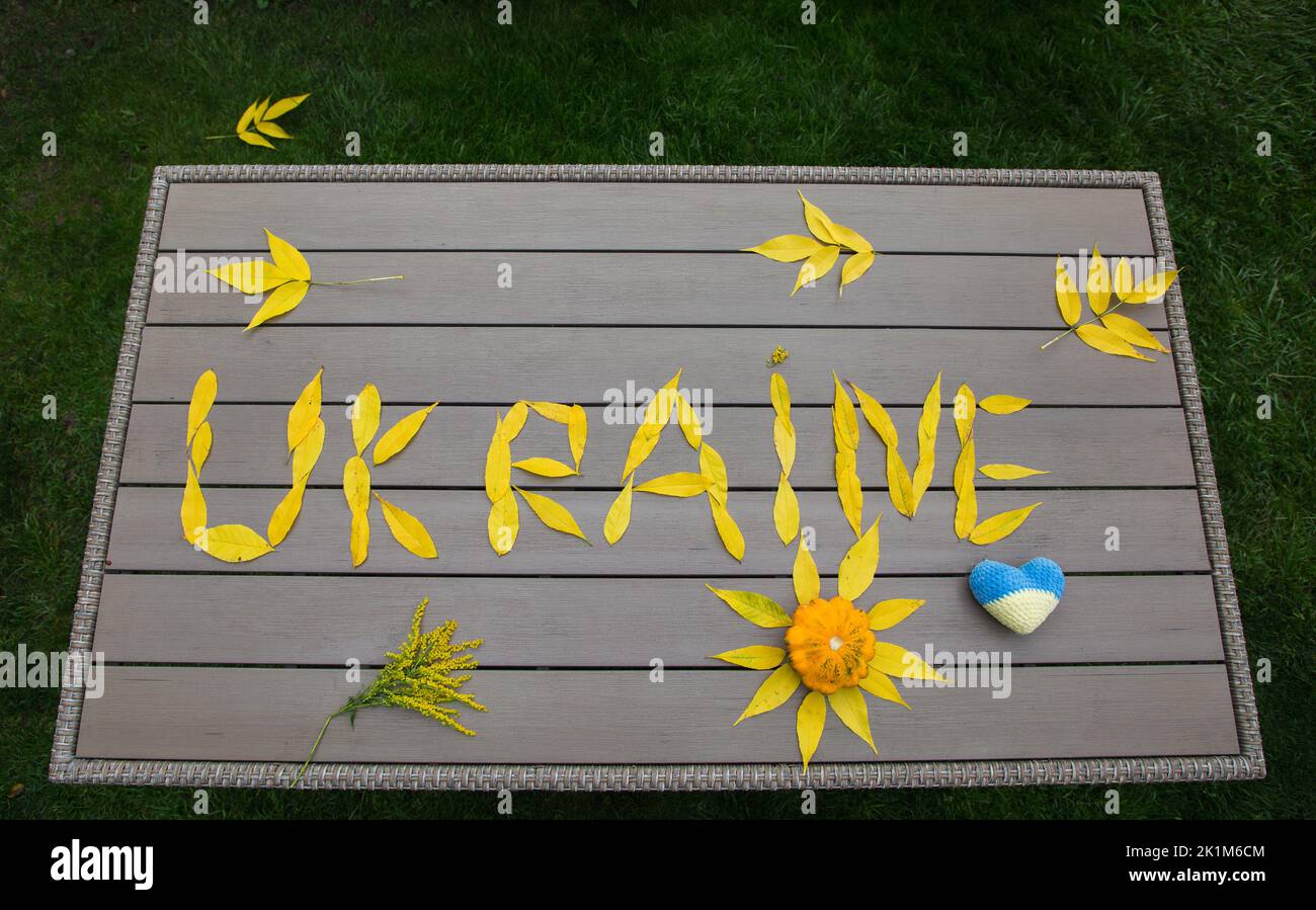 word Ukraine, laid out from fallen yellow autumn leaves on table in garden. Ukrainians want peace. concept of supporting Ukrainian people, drawing att Stock Photo