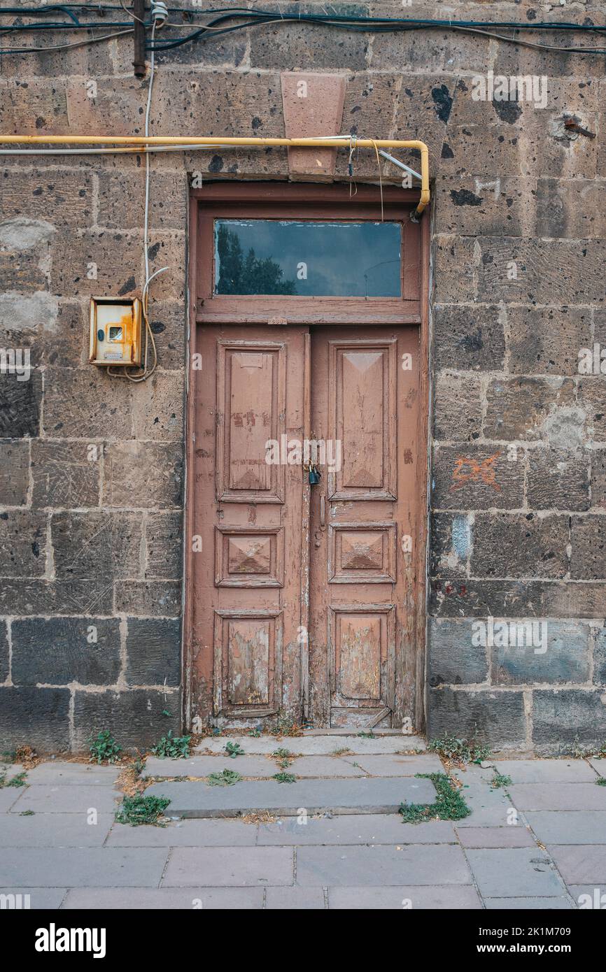 Old classical stone house with rustic, brown, carved, vintage wooden door. Door textures and backgound. High quality photo. Stock Photo