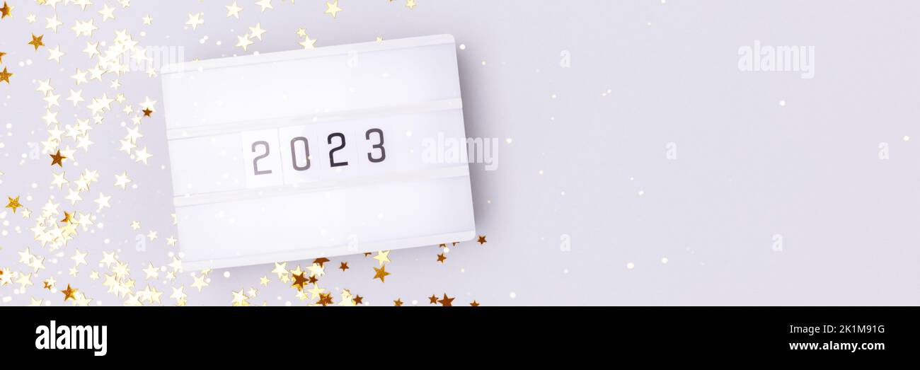 Banner with lightbox with 2023 numbers on a blue background with golden stars confetti. Copy space. Stock Photo