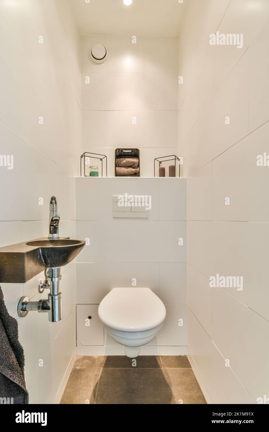 partition between shower tap and wall hung toilet in modern restroom at