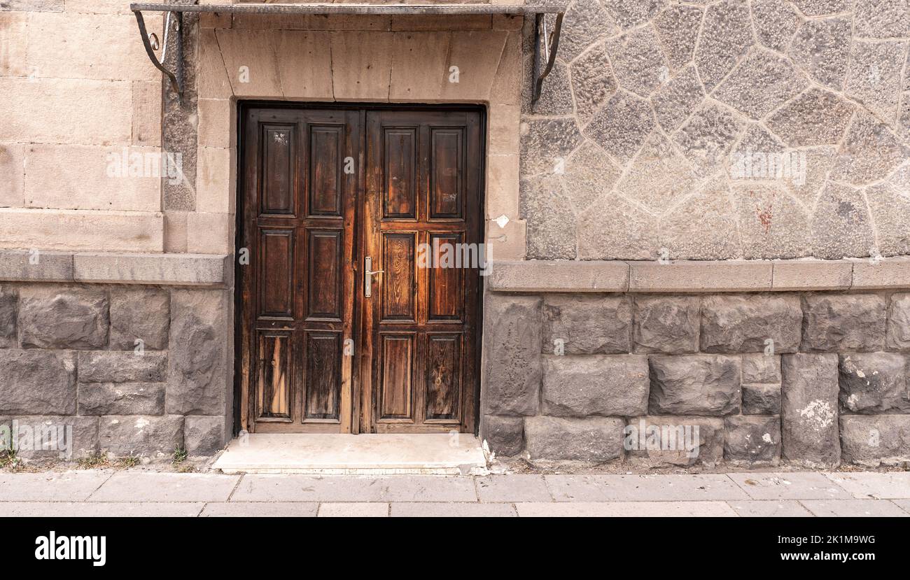 Old classical stone house with rustic, brown, carved, vintage wooden door. Door textures and backgound. High quality photo. Stock Photo