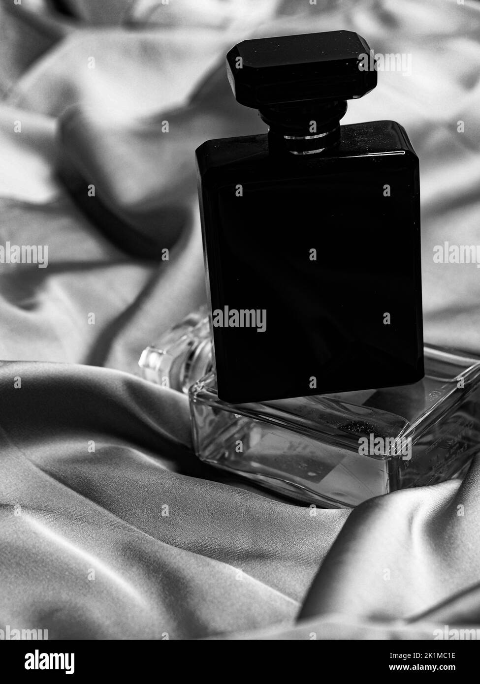 A vertical black and white shot of perfume bottles on top of each other
