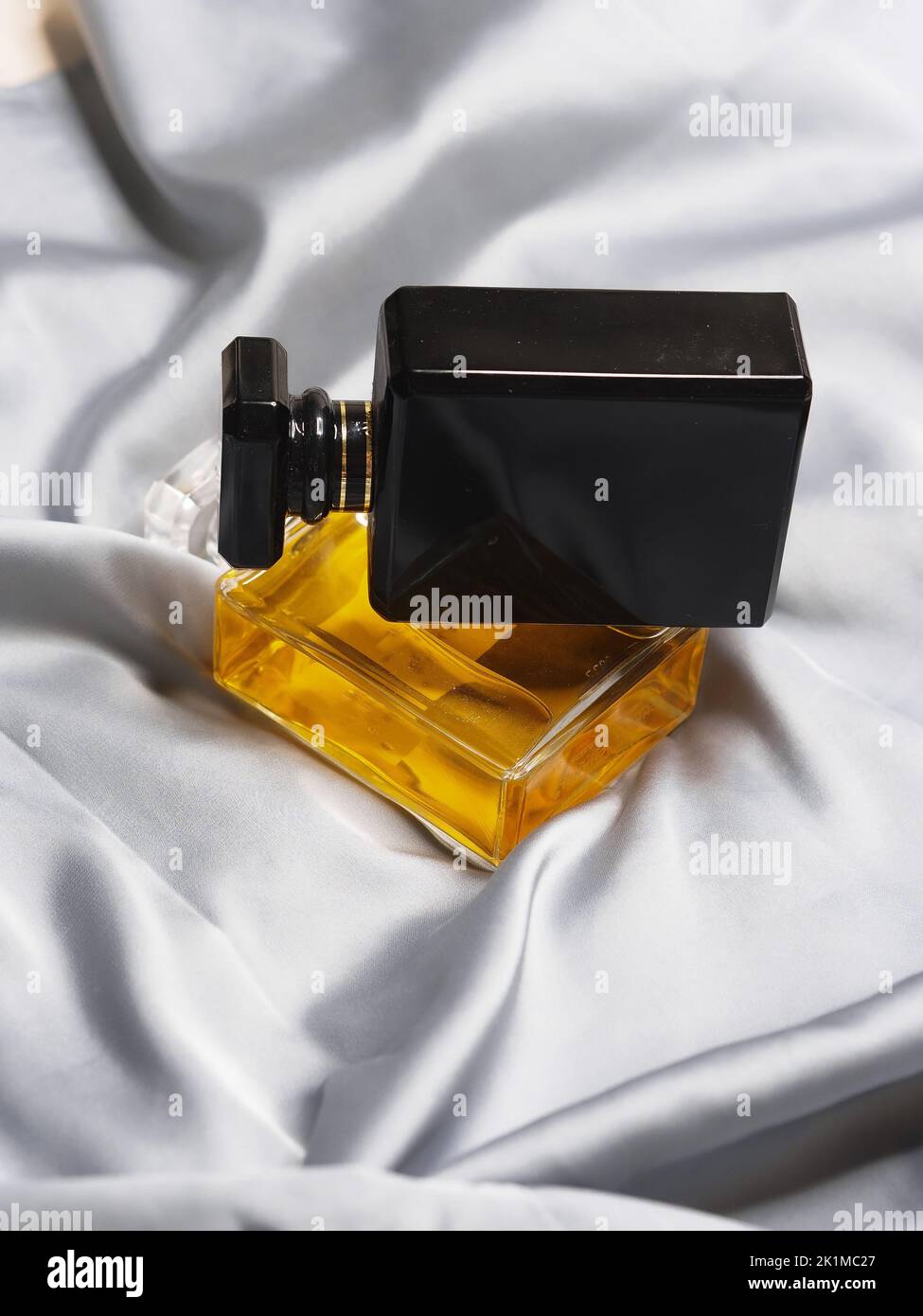 A vertical shot of perfume bottles on top of each other on bed sheets