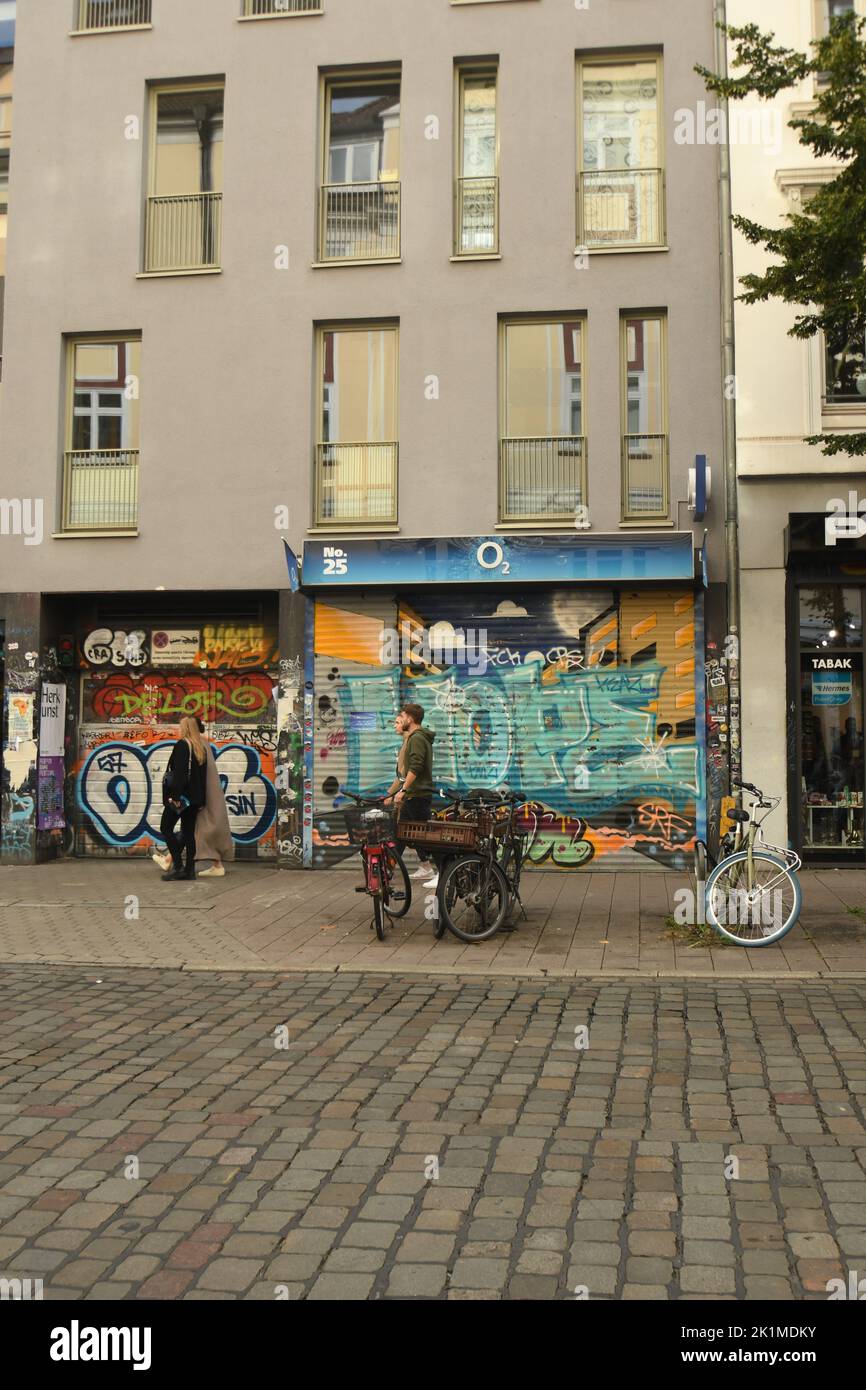 The vertical view of bicycles and people before the buildings with graffiti art in Hamburg Stock Photo
