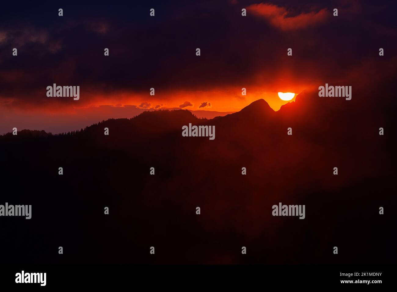 dramatic sunset with clouds and the sun in the Alpine foothills of Fribourg Stock Photo