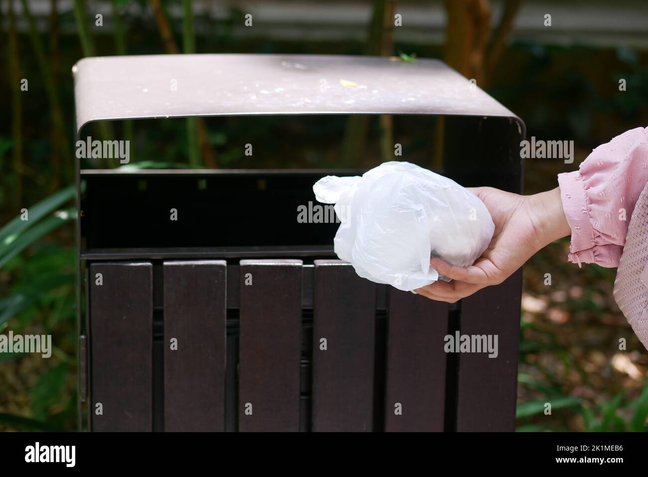 women hand throwing an empty plastic bag in the garbage trash or bin
