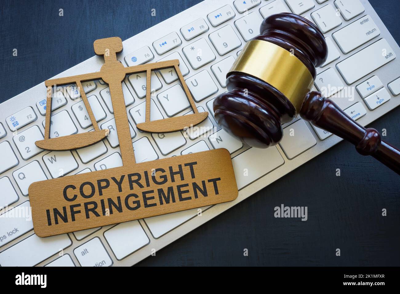 Copyright infringement phrase on the plate, keyboard and gavel. Stock Photo