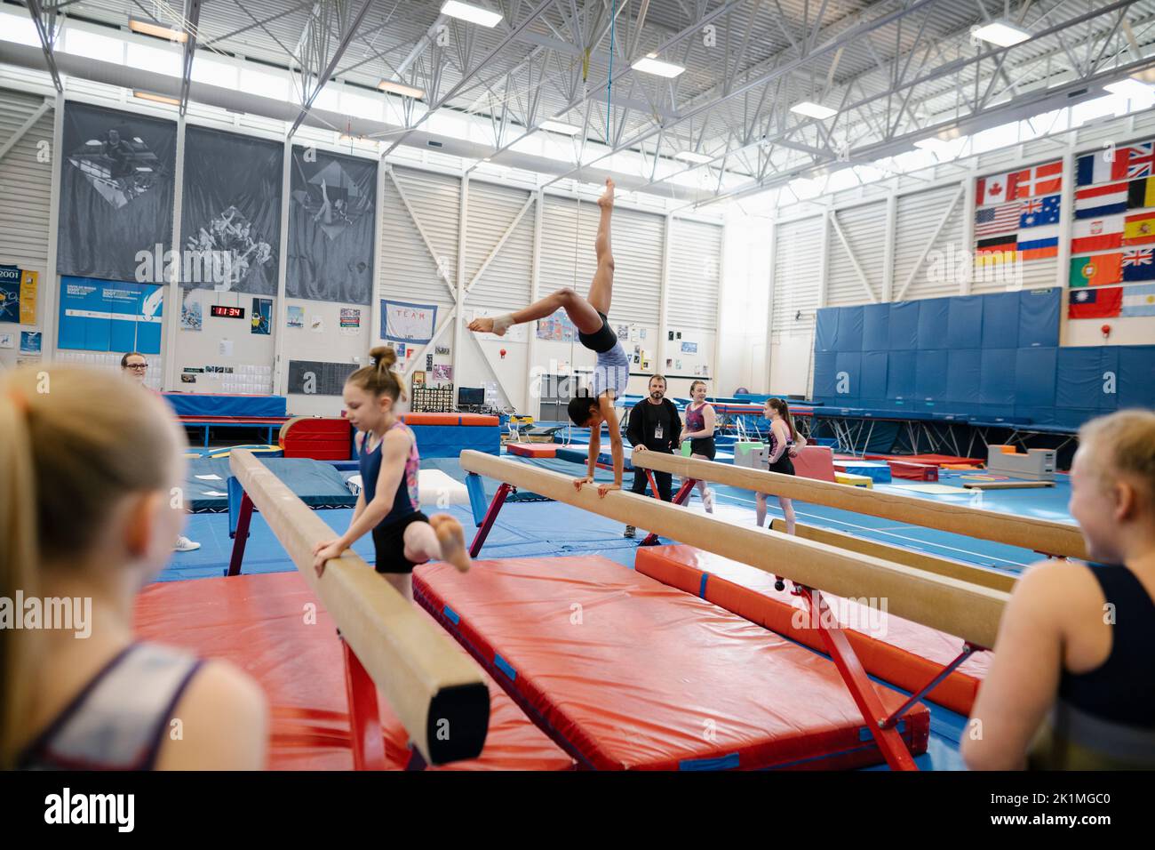 Girl doing handstand on balance beam in gymnasium Stock Photo Alamy