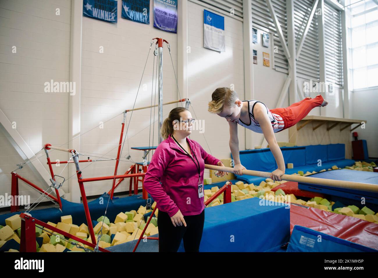 Coach training boy on gymnastic bar Stock Photo Alamy