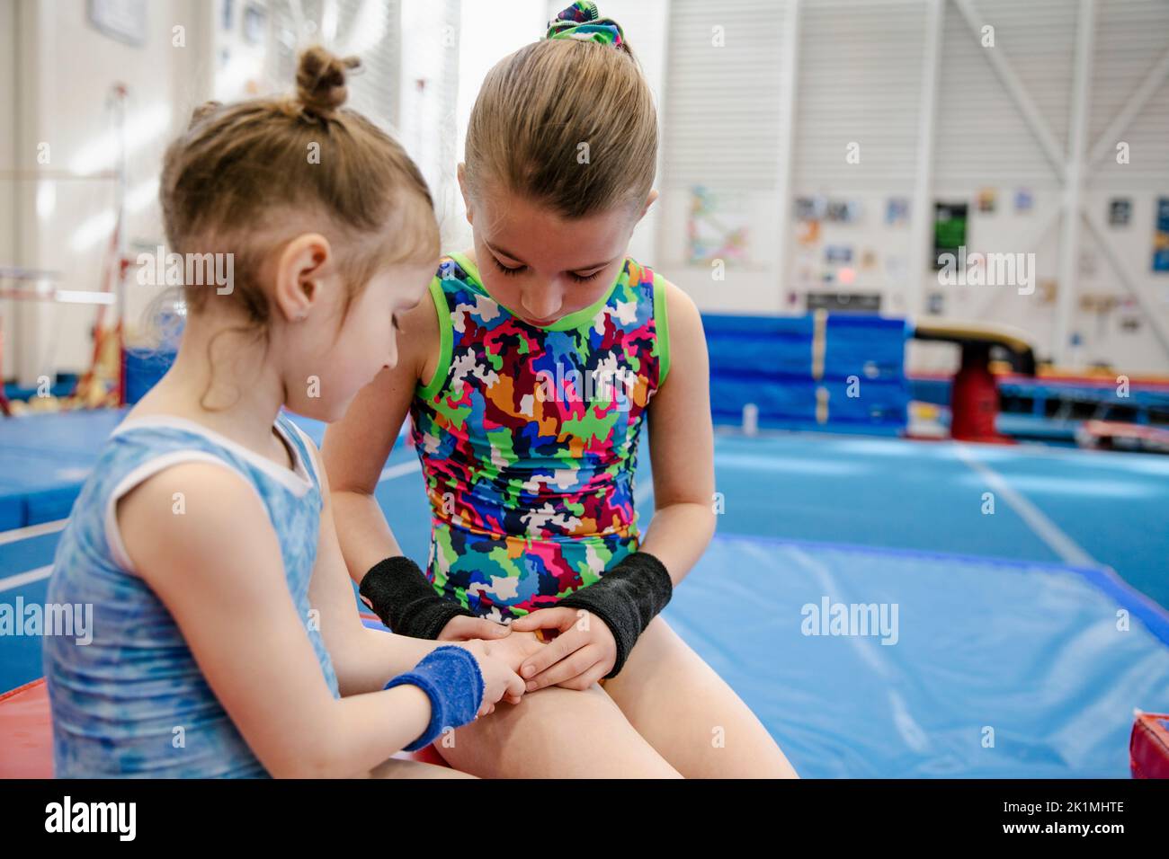 Older girl checking younger girl's hand in gymnasium Stock Photo Alamy