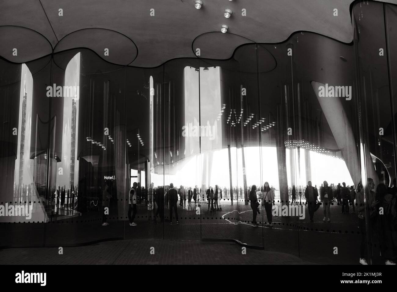 The grayscale view of people reflection on the curved wavy mirror facade on Elbphilharmonie Stock Photo