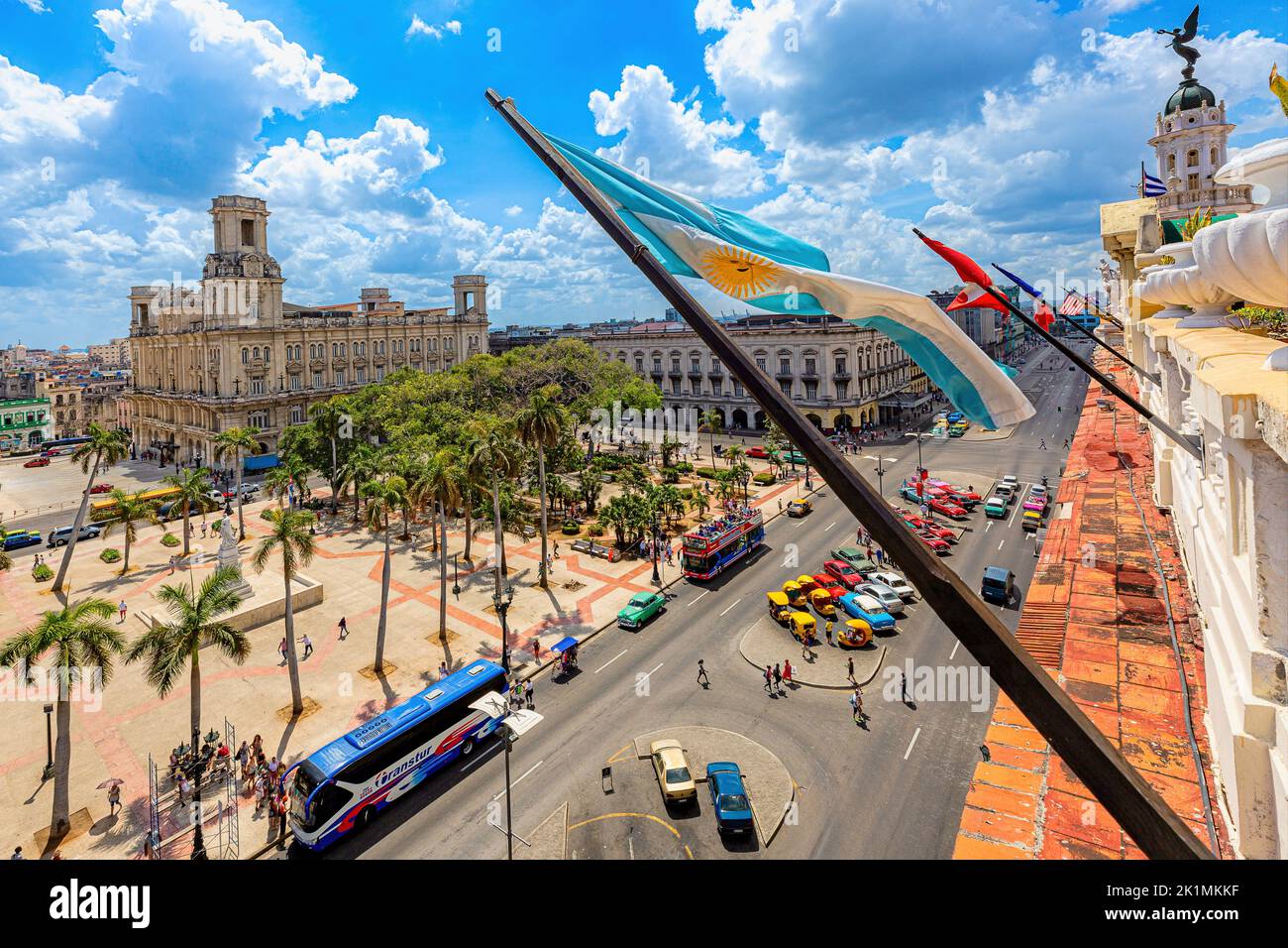 A closeup shot of different flags on top of Hotel Inglaterra in downtown Cuba with cars passing on the street Stock Photo
