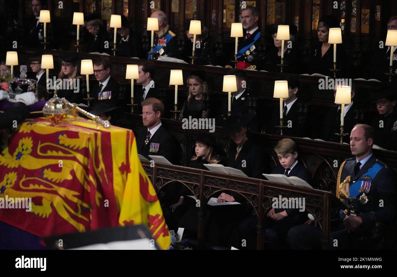 (front row, left to right) The Duke of Sussex, Princess Charlotte, the Princess of Wales, Prince George, and the Prince of Wales, watch as the Imperial State Crown and the Sovereign's orb and sceptre are removed from the coffin of Queen Elizabeth II, draped in the Royal Standard, during the Committal Service at St George's Chapel in Windsor Castle, Berkshire. Picture date: Monday September 19, 2022. Stock Photo