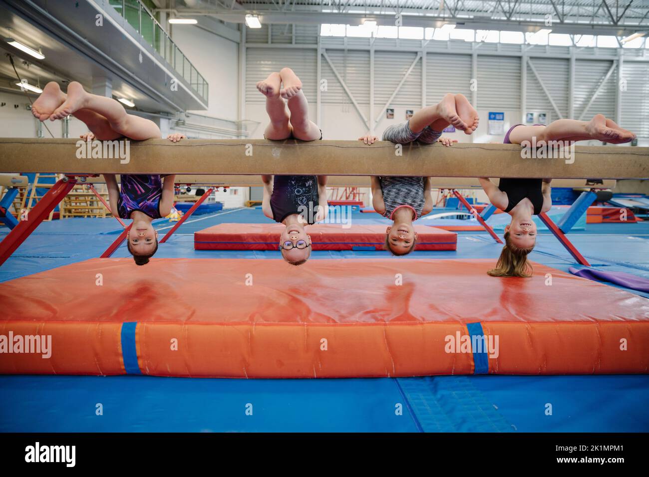 Four girls upsidedown on balance beam Stock Photo