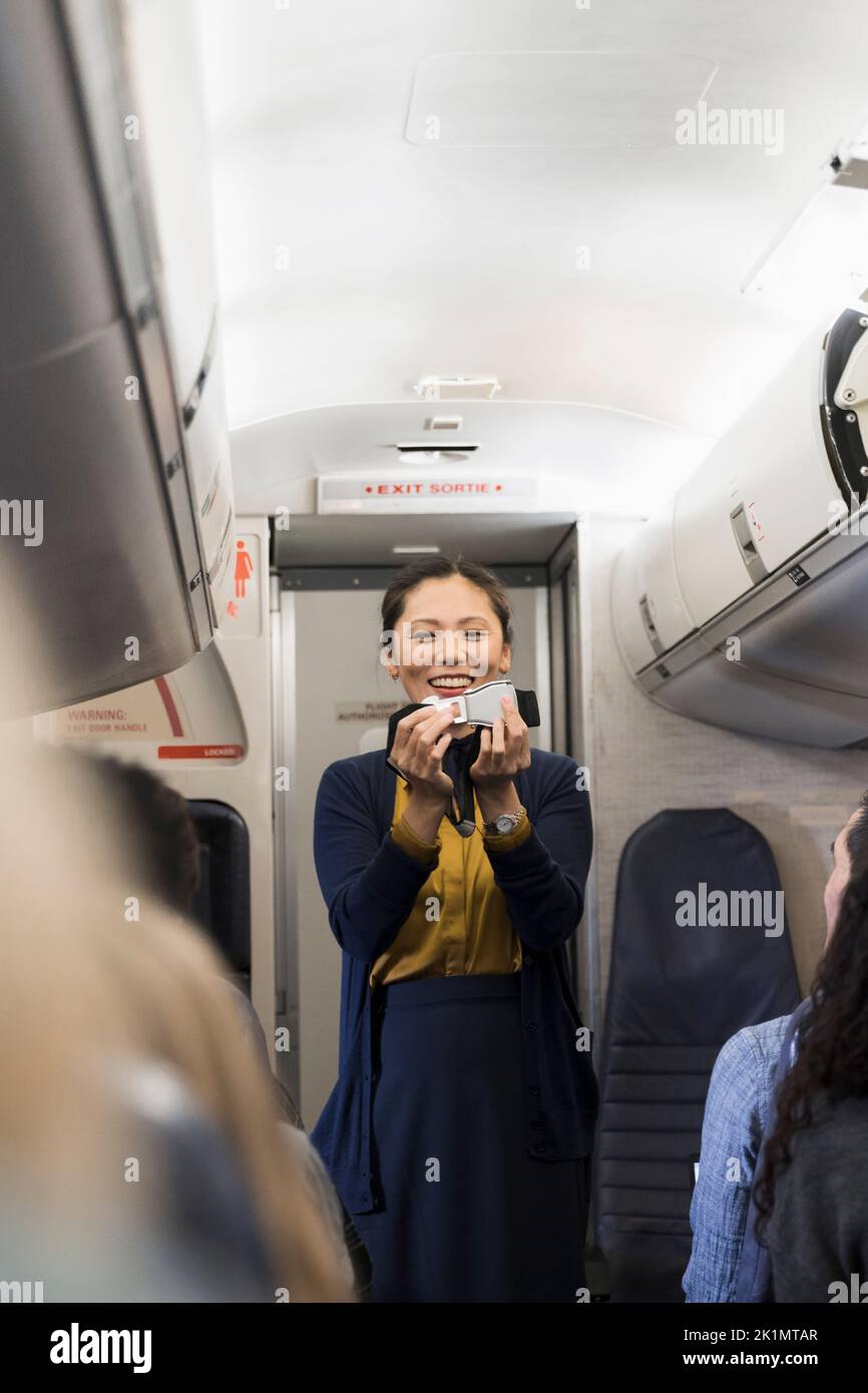 Female flight attendant demonstrating seat belt safety in airplane