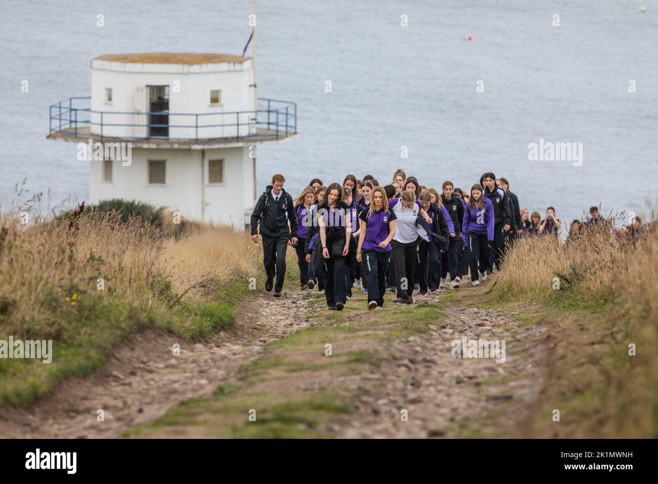 Children and teachers from Gordonstoun School marks the state funeral of Queen Elizabeth II by walking to the Coastguard watchtower at nearby Covesea was opened by Prince Philip in 1955 and was used by King Charles III during his time as a Captain of the Coastguard Service at Gordonstoun. Picture date: Monday September 19, 2022. Stock Photo